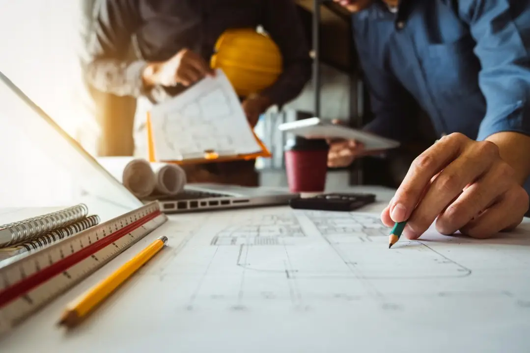 Team reviewing and marking up construction plans at a desk